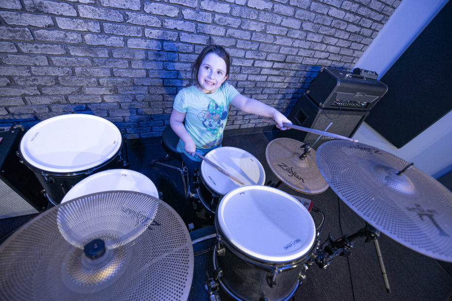 Young girl plays drums.